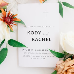 Puede incluir: Tarjeta de anuncio de boda con fondo blanco y texto negro. El texto dice "Bienvenido a la boda de Kody y Rachel, sábado 26 de agosto de 2023, a la una de la tarde, Iglesia Católica de Santa María, Iowa City, IA".