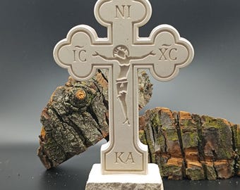 May include: A white, carved wooden cross with a figure of Jesus Christ on it. The cross has the letters "IC XC NI KA" inscribed on it.