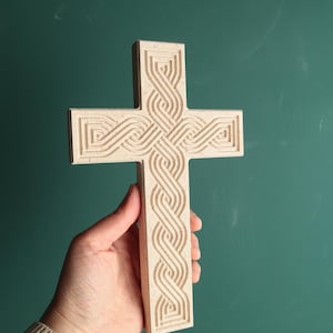 May include: A beige wooden cross with an intricate Celtic knot design carved into the surface.