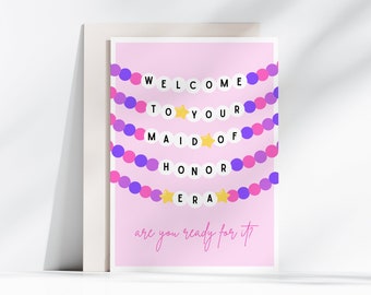 May include: A pink card with a purple and pink garland that spells "WELCOME TO YOUR MAID OF HONOR ERA" with gold stars. The text "are you ready for it?" is written below the garland.