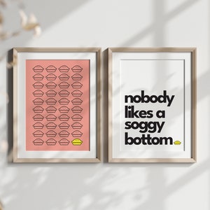 May include: Two framed prints with a pink background and black text. The left print has a grid of black pie outlines with one yellow pie outline. The right print has the text "nobody likes a soggy bottom" with a yellow pie outline at the end.