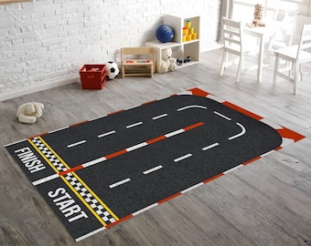 May include: A rectangular area rug featuring a dark gray asphalt road design with white dashed lane markings, a red and white checkered finish line, and the words START and FINISH printed in white capital letters on a black background.
