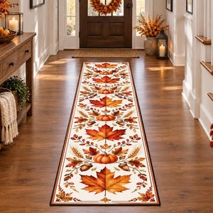 Peut inclure: Un long tapis de couloir rectangulaire au fond crème, orné d'un motif répétitif de citrouilles orange, de feuilles d'érable rouges et jaunes vives, de glands marron et d'épis de blé dorés, le tout bordé d'un fin cadre marron foncé.