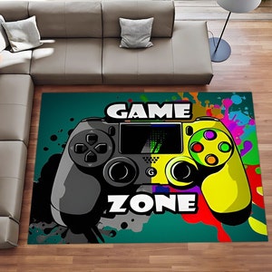 Puede incluir: Una alfombra de mando de juego verde, amarillo y negro con las palabras "GAME ZONE" impresas en ella. La alfombra tiene un diseño de salpicaduras de pintura de colores.