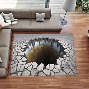 May include: A rectangular area rug featuring a 3D optical illusion of a deep, jagged chasm in cracked, dry earth. The design displays a gray, rocky surface surrounding a dark, cavernous hole with golden-yellow interior walls and sharp edges.