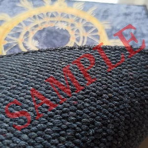 K&ouml;nnte beinhalten: Nahaufnahme eines dunkelblauen Stoffes mit einer strukturierten Oberfl&auml;che. Das Wort "SAMPLE" ist in roten Buchstaben auf dem Stoff gedruckt.