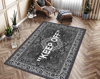May include: A rectangular area rug featuring a black and white intricate floral pattern with the text "KEEP OFF" printed in large white capital letters across the center. The rug has a detailed border and a high-contrast monochromatic design.