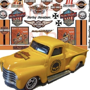 May include: A yellow toy pickup truck with a Harley-Davidson logo on the side. The truck has a black skull logo on the side and a Harley-Davidson logo on the hood. The truck is surrounded by various Harley-Davidson logos.