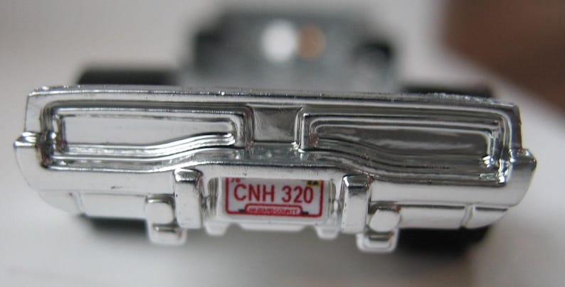 May include: A silver toy car with a red license plate that reads "CNH 320" and the words "NEW JERSEY" in smaller font.