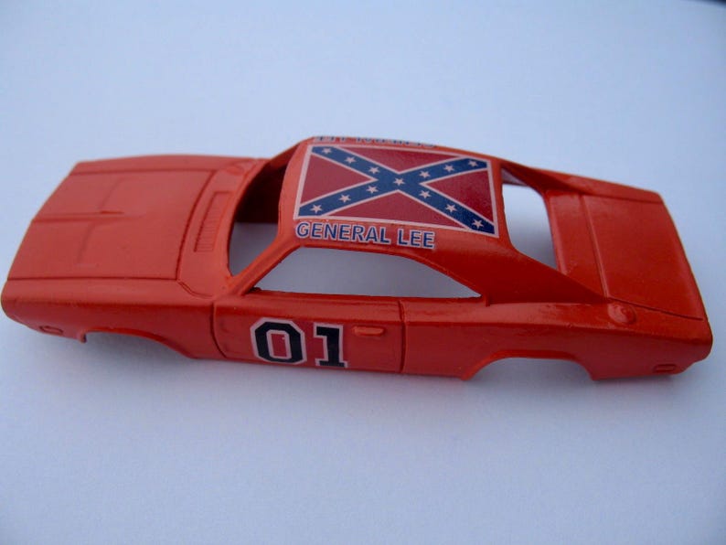 May include: A red toy car model of the General Lee, a 1969 Dodge Charger from the TV show The Dukes of Hazzard. The car has a Confederate flag on the roof and the number 01 on the side.