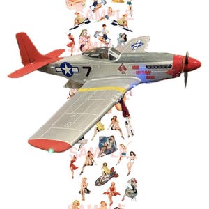 Könnte beinhalten: Ein silbernes und rotes Flugzeugmodell mit Pin-up-Girl-Aufklebern. Das Flugzeug ist eine P-51 Mustang mit einem gelben Streifen auf dem Flügel. Die Aufkleber zeigen Frauen in verschiedenen Posen, einige mit Sternen und Streifen, andere mit Herzen und Pik. Das Flugzeug hat einen roten Schwanz und eine rote Nase.
