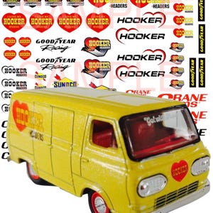 May include: A yellow vintage van with a red heart logo that says "Hooker Headers" on the side. The van has a white roof and a red stripe around the windows. The van is surrounded by various stickers and logos, including "Good Year Racing", "Sunoco", and "Crane"