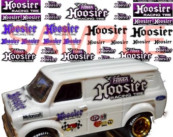 May include: A white van with gold wheels and a "HIMA Hoosier Racing Tire" logo on the side. The van has other logos and stickers on the side, including "Motorcraft" and "STP".