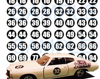 May include: A set of black and white round stickers with numbers from 16 to 94. The stickers are arranged in rows of eight. A white toy car with a black number 32 on the side is in the foreground.