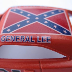 May include: A red toy car with a Confederate flag on the roof and the words "GENERAL LEE" printed on the side.