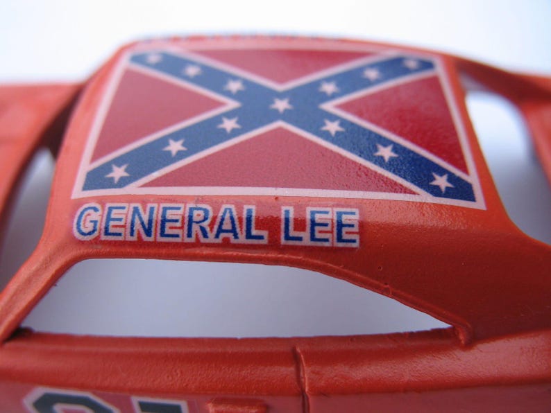 May include: A red toy car with a Confederate flag on the roof and the words "GENERAL LEE" printed on the side.