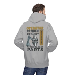 May include: A light gray hooded sweatshirt with the text "OPERATOR RETIRED and REBUILT AFTERMARKET PARTS" and an illustration of a knee joint and a backhoe. The words "BODY CONTAINS" are printed vertically on the right side.