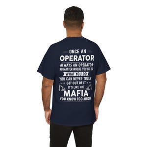 Könnte beinhalten: Marineblaues T-Shirt mit weißem Text: "ONCE AN OPERATOR ALWAYS AN OPERATOR...IT'S LIKE THE MAFIA YOU KNOW TOO MUCH." Das Design enthält zwei Bagger-Grafiken.
