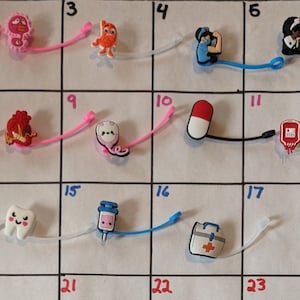 May include: A white grid with numbers 1 through 24 printed in blue. Each square contains a small colorful charm with a medical theme. The charms include a brain, a tooth, a syringe, a first aid kit, a pill, a blood bag, a stethoscope, a heart, a lung, a doctor, a nurse, and a fire extinguisher. The word "MED" is printed in black at the bottom of the grid.