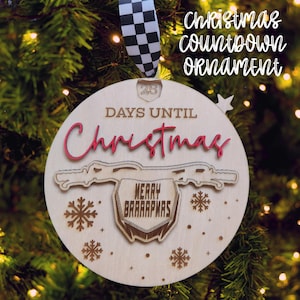 May include: A wooden Christmas countdown ornament with the text "Christmas Countdown Ornament". The round ornament has the words "Days Until Christmas" and "Merry Braaapmas". It is decorated with snowflakes and a motorcycle design.