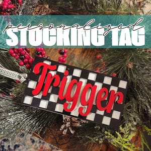 May include: A black and white checkered stocking tag with the name "Trigger" written in red letters.
