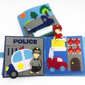May include: A felt book for children with a police car, a fireman, and a fire truck. The book has a blue cover and is made of felt.