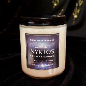 May include: A soy wax candle in a clear glass jar with a black lid. The label reads "NYKTOS" and "smells like..." with the text "HOMESWEETFARMNJ" at the top. The candle is 8 oz and has a burn time of 40+ hours.
