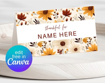 Puede incluir: Una tarjeta plegada con un diseño floral con flores amarillas, marrones y blancas. La tarjeta tiene el texto "thankful for NAME HERE" en marrón. Un gráfico circular en la esquina inferior izquierda dice "edit free in Canva".