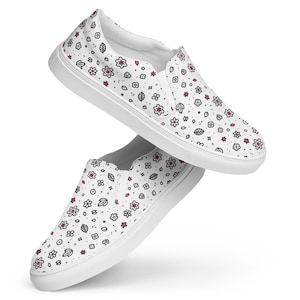 May include: A pair of white slip-on canvas shoes with a black and pink floral pattern.