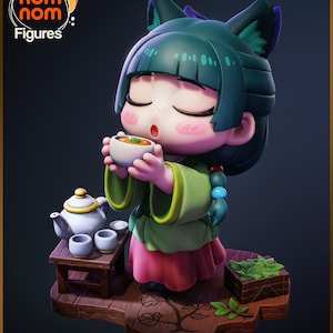 May include: A figurine of a girl with green hair and fox ears, dressed in a green and pink outfit, enjoying tea. A white teapot, cups, and a small wooden table are next to her. The figurine is on a wooden base with the "nom nom Figures" logo.