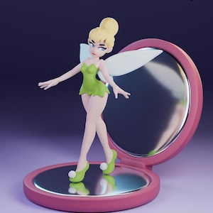 May include: A figurine of a fairy with blonde hair in a bun, wearing a green dress and shoes, and white wings. The fairy is standing on a pink compact mirror. The text "lavender + devilry" is in the upper right corner.