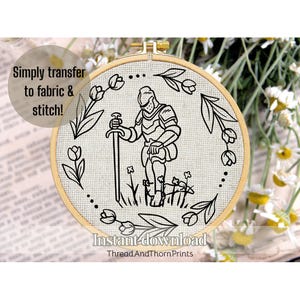May include: An embroidery hoop with a black and white line drawing of a knight kneeling, holding a sword, surrounded by flowers and leaves. The text "Simply transfer to fabric & stitch!" and "Instant download" are also included.