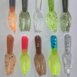 May include: Assortment of 12 soft plastic fishing lures in various colors, including green, white, orange, pink, brown, blue, and silver. The lures have a long, thin body with multiple tentacles.