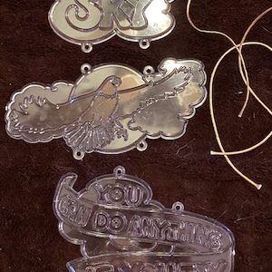 May include: Three clear plastic ornaments with inspirational messages. The first ornament has the text "To the Sky". The second ornament has a picture of an eagle flying in the clouds. The third ornament has the text "You can do anything if you try".
