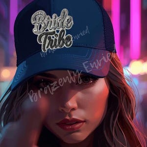 May include: A navy blue baseball cap with the text "Bride Tribe" in a sparkly, silver design. The cap has a mesh back and a curved brim. The image is a close-up of a person wearing the cap.