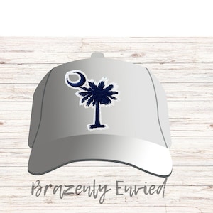 May include: A gray baseball cap with a white and blue embroidered design of a palmetto tree and crescent moon. The text "Brazenly Envied" is printed on the bottom of the cap.