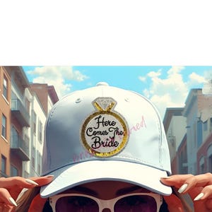 May include: White baseball cap with a diamond ring design and the text "Here Comes The Bride". The ring is gold with a silver diamond. The word "married" is written in pink on the side of the cap. Perfect for a bachelorette party.