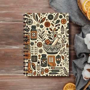 May include: A cream-colored spiral notebook with a colorful pattern of herbs, plants, and apothecary items. The pattern includes a mortar and pestle, bottles, pills, and stars.