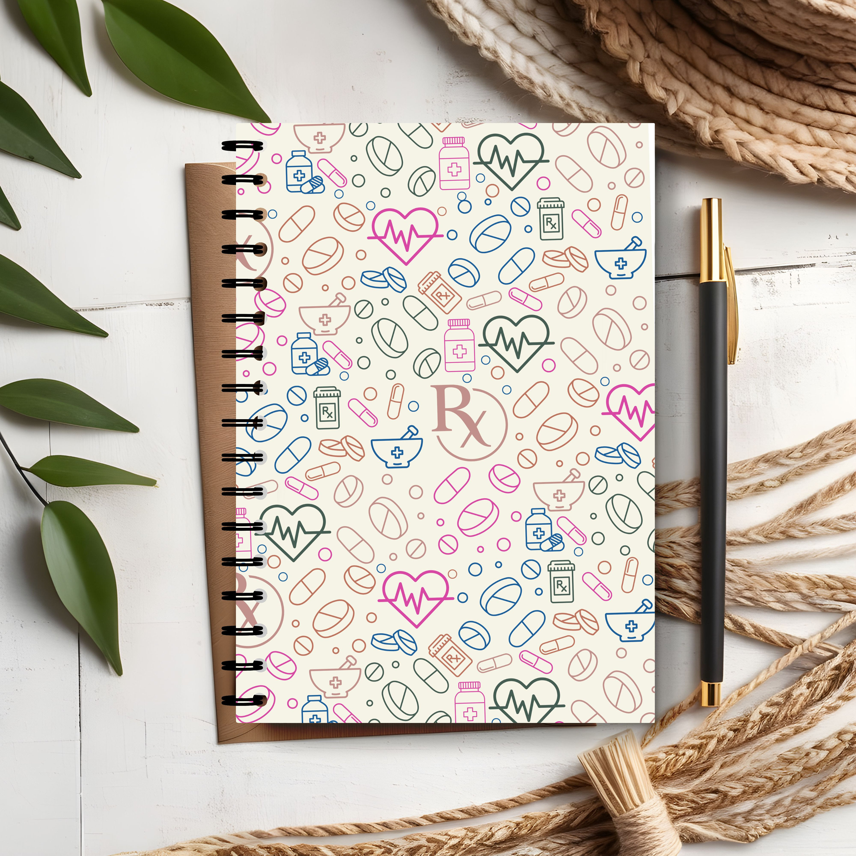 May include: A cream-colored spiral notebook with a colorful pattern of hearts, pills, and medical symbols. The notebook has a brown spine and a white background.