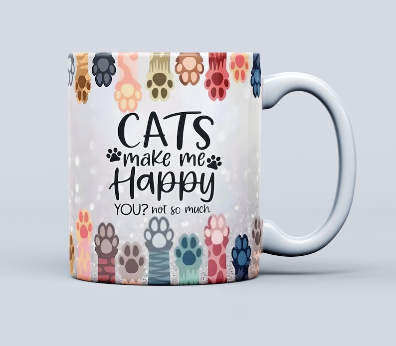Pu&ograve; includere: Tazza in ceramica bianca con un design avvolgente con impronte di zampe di gatto colorate e la scritta "CATS make me Happy YOU? not so much." La tazza ha un manico bianco ed &egrave; adatta a bevande calde o fredde.