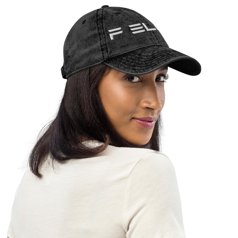 May include: A black distressed denim baseball cap with a white embroidered logo that says "FELA".
