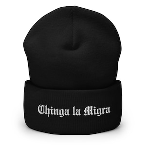 May include: Black beanie with the text "Chinga la Migra" in white gothic font. The beanie is made of a soft, knitted material and has a folded cuff. A warm and stylish accessory for cold weather.