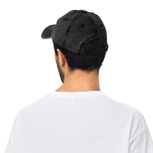 May include: A black denim baseball cap with a slightly distressed look. The cap has a curved brim and a back strap with a buckle.