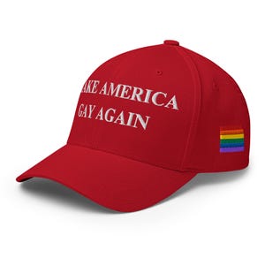 Op de afbeelding: Rode baseballpet met witte geborduurde tekst "Make America Gay Again" en een regenboog-pride-vlagpatch aan de zijkant.