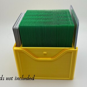May include: A yellow plastic card holder with a green deck of cards inside. The text "Cards not included" is printed below the holder.
