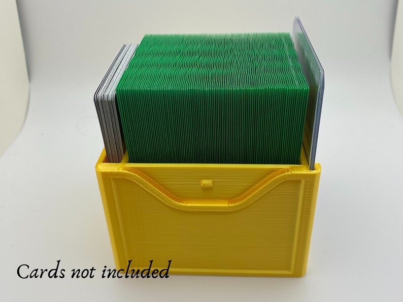 May include: A yellow plastic card holder with a green deck of cards inside. The text "Cards not included" is printed below the holder.