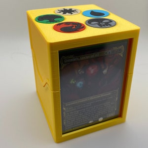 May include: Yellow card deck box with a clear window showing a Magic: The Gathering card with the text "Omnath, Locus of All". The top of the box has five colored symbols.