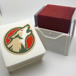 May include: White card storage box with a wolf logo on the front. The box is open and a stack of red cards is visible inside.