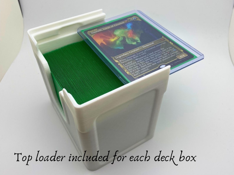 May include: White plastic deck box with a green deck of cards inside. A clear plastic top loader with a Magic: The Gathering card is on top of the box. The card is "Legendary Creature - Elemental".