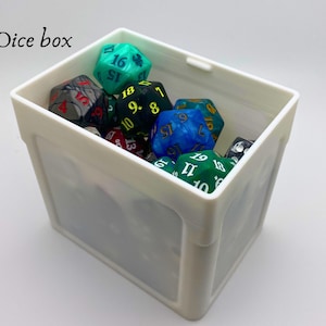 May include: A white plastic dice box filled with colorful dice. The dice have black and white numbers and some have green and blue swirls.